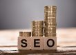 Closeup of SEO text written on wooden blocks with stacked coins