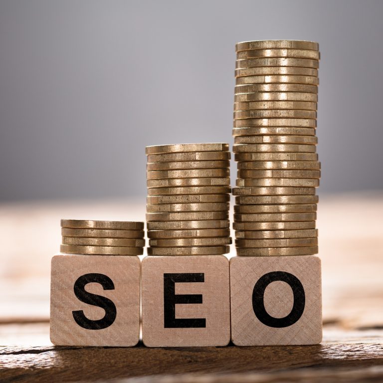 Closeup of SEO text written on wooden blocks with stacked coins